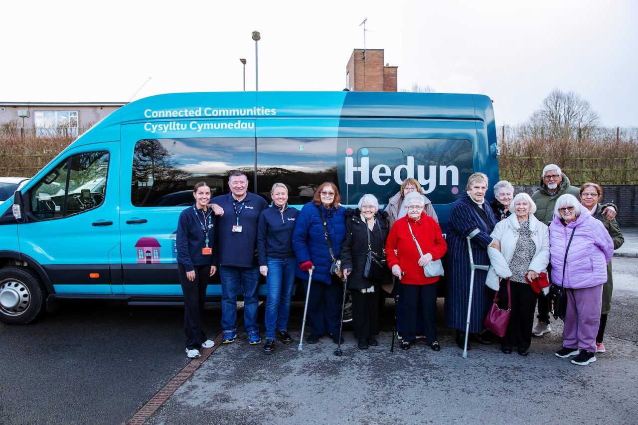 Mae cydweithwyr a thrigolion Hedyn yn sefyll o flaen bys Hedyn.