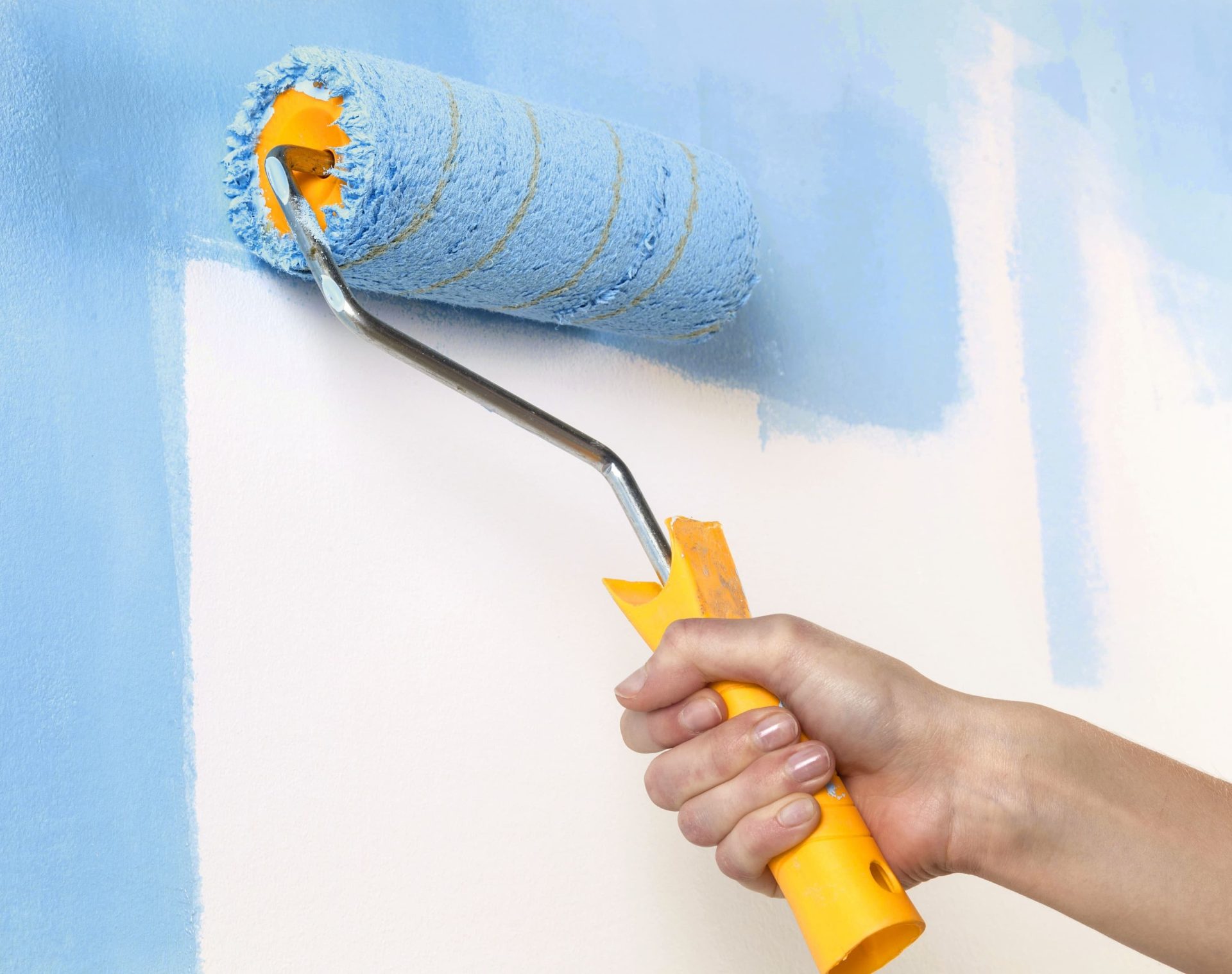 A close up of someone painting a wall with a roller.